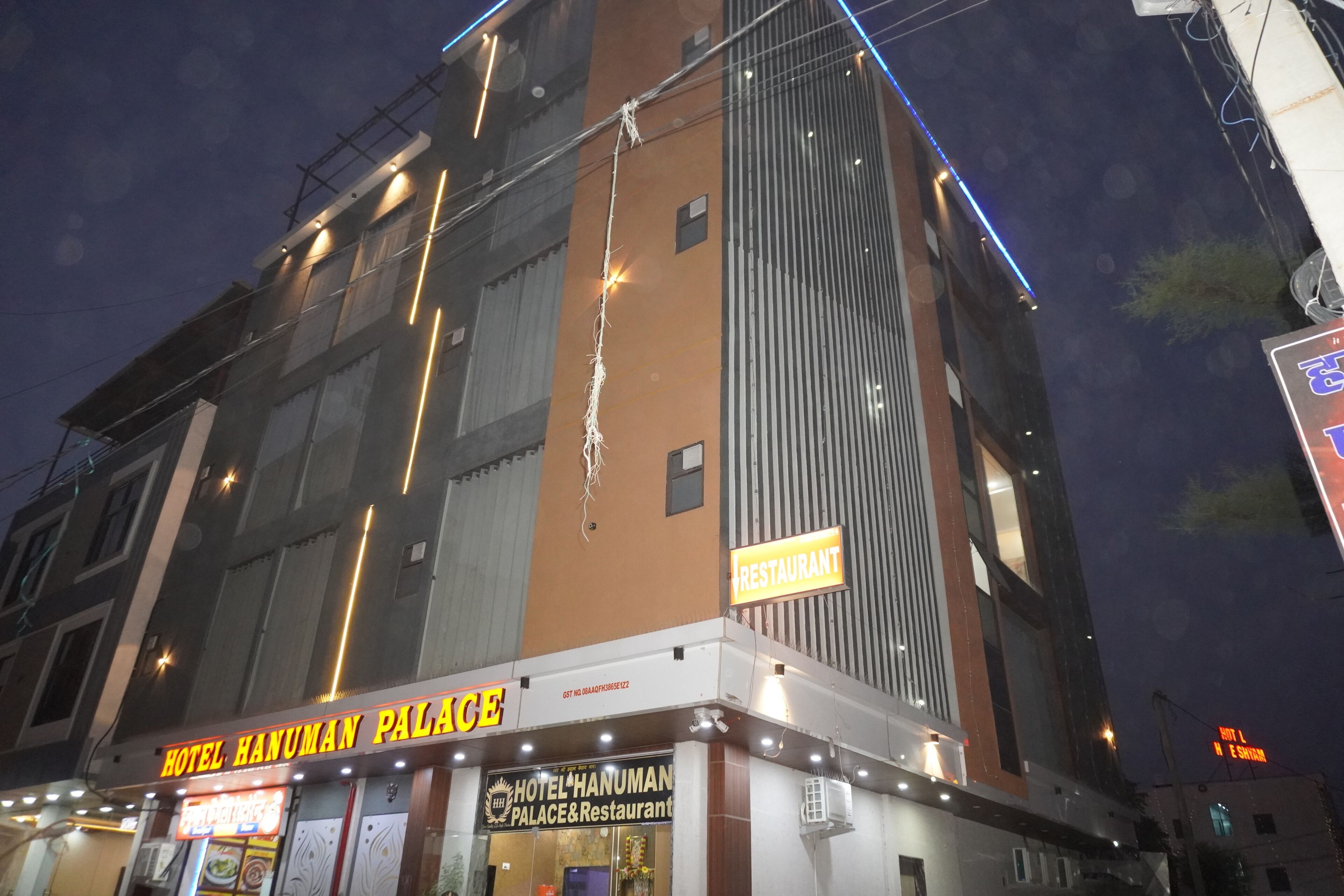 A hotel with a sign reading "HOTEL HANUMAN PALACE" and "RESTAURANT" indicating it offers both lodging and dining services.