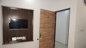 A room with a wooden door, a wall-mounted television, and a door with a number plate. - Hotel Hanuman Palace (Danta Ramgarh)