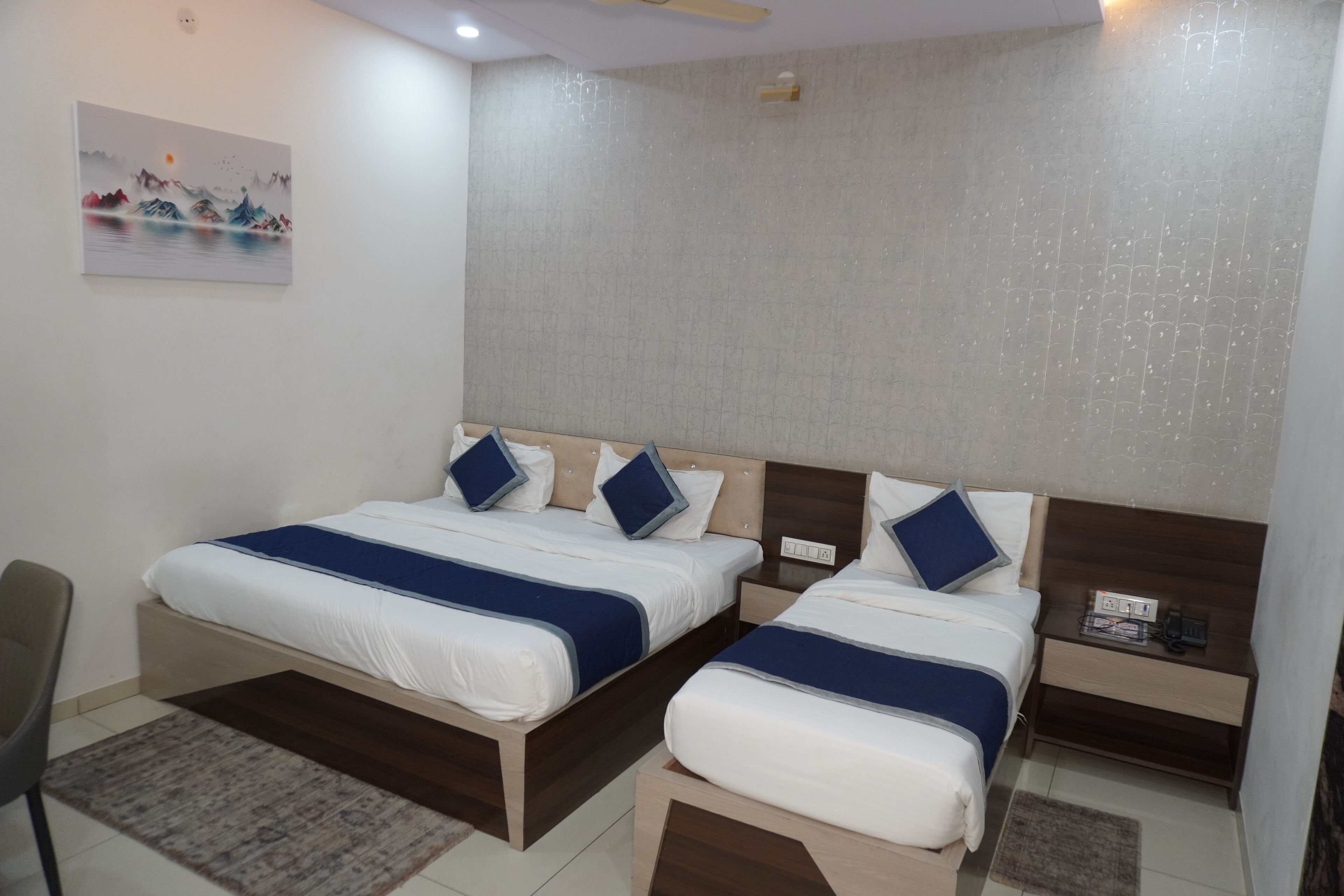 Habitación de hotel con dos camas, un escritorio, una silla y un cuadro en la pared.