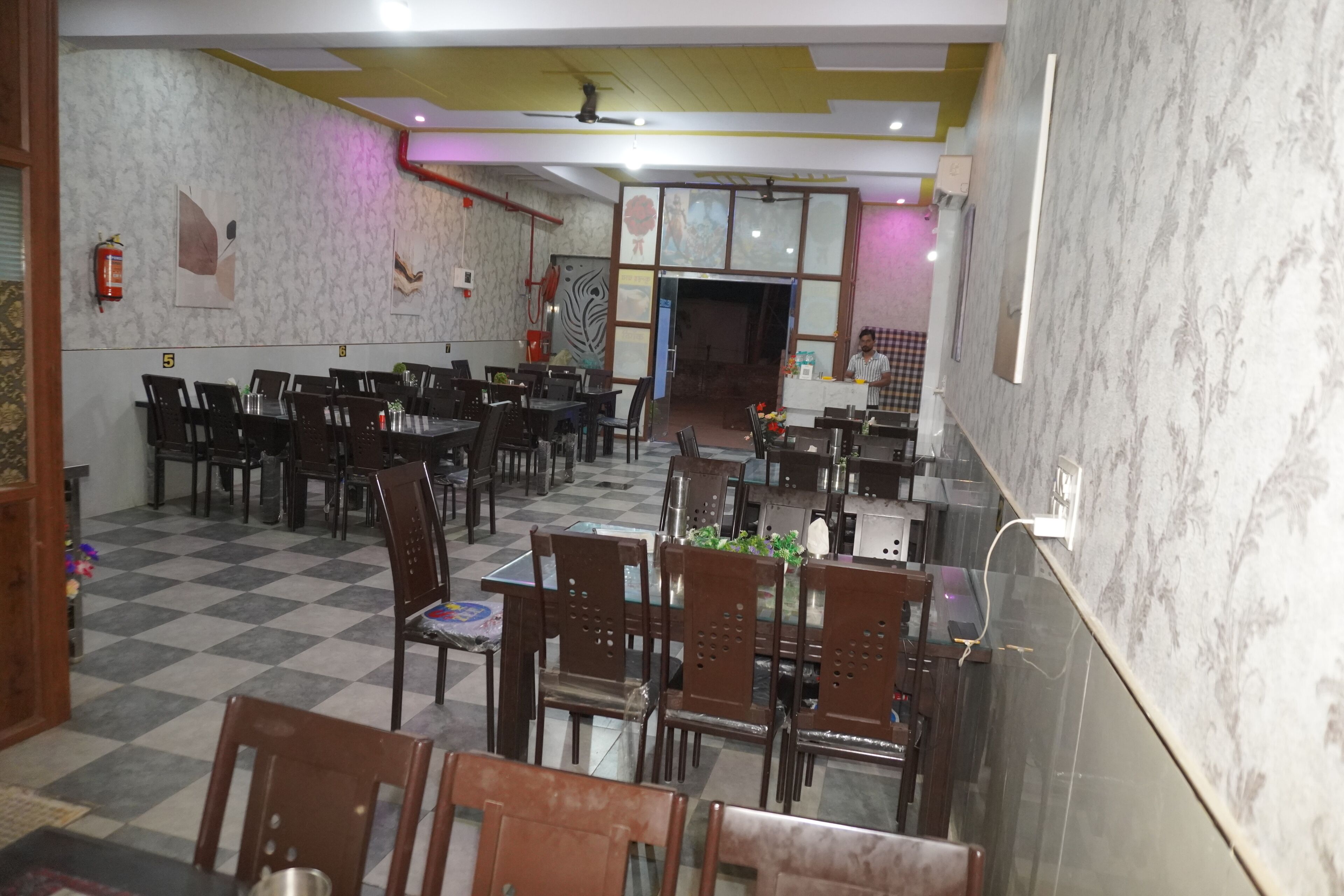 A restaurant with multiple tables and chairs, checkered floor, and decorative wall panels.