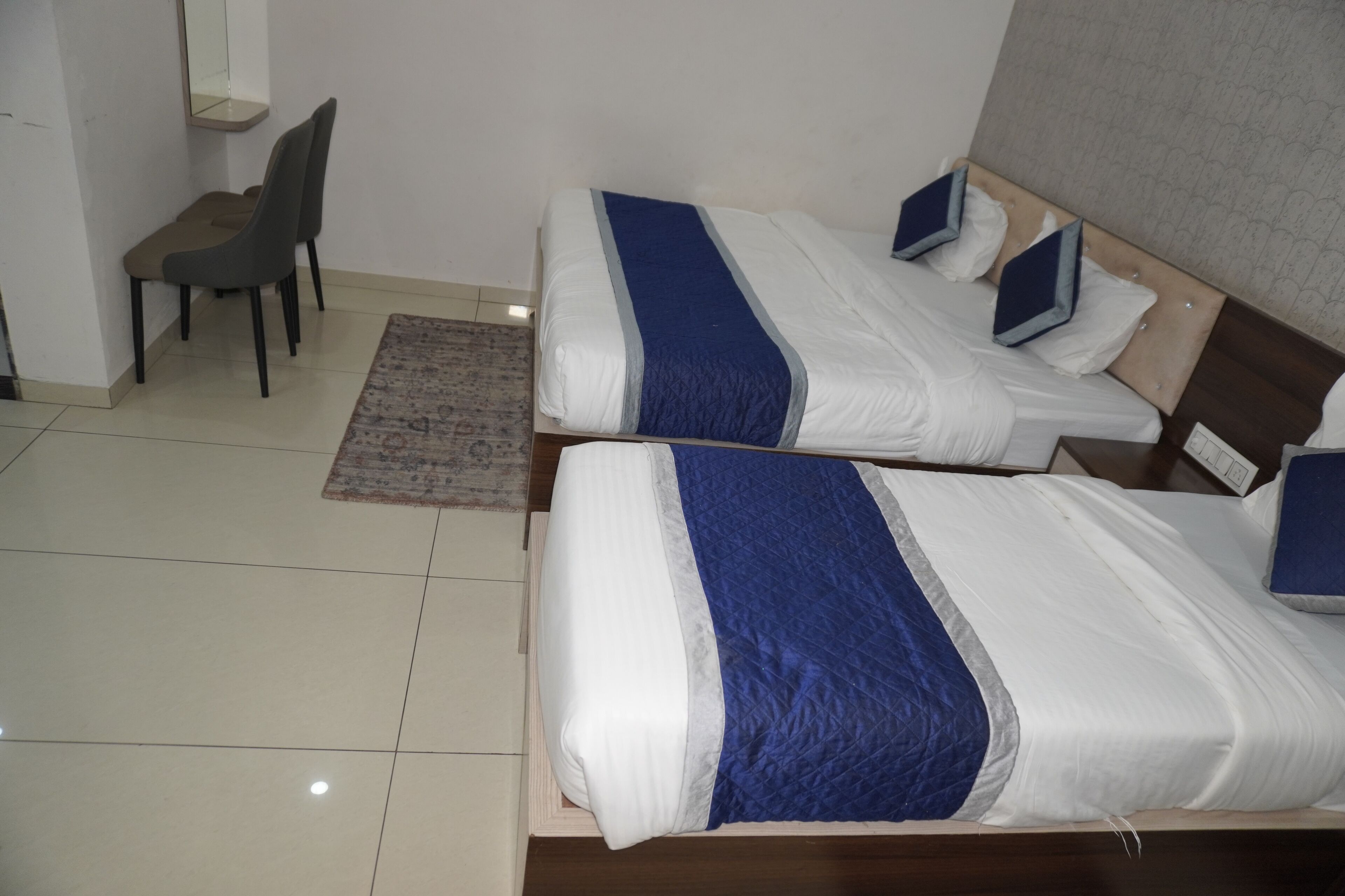 A hotel room with two beds, a desk, and a chair.