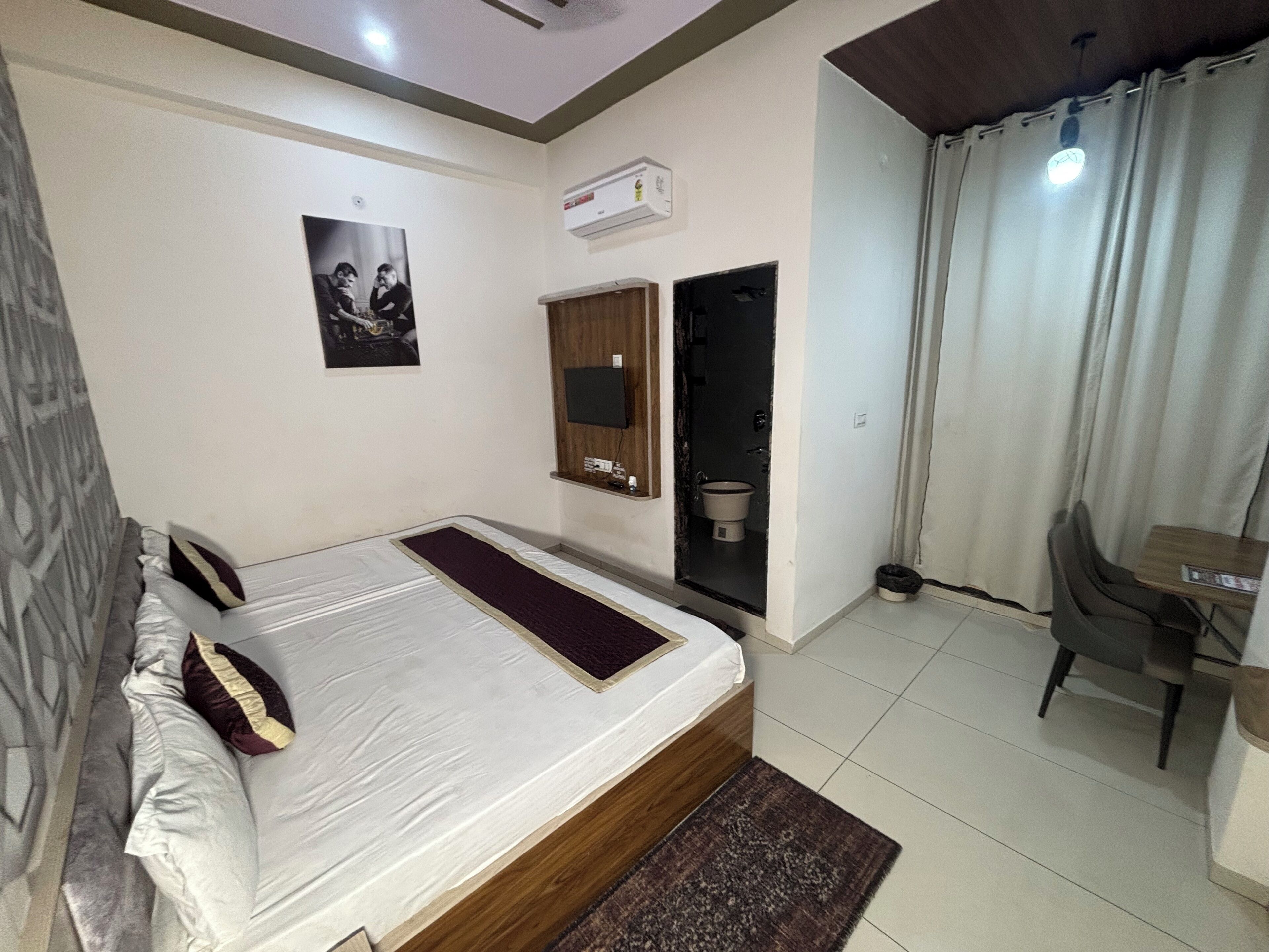 A bedroom with a bed, a desk, a chair, a toilet, and a shower.