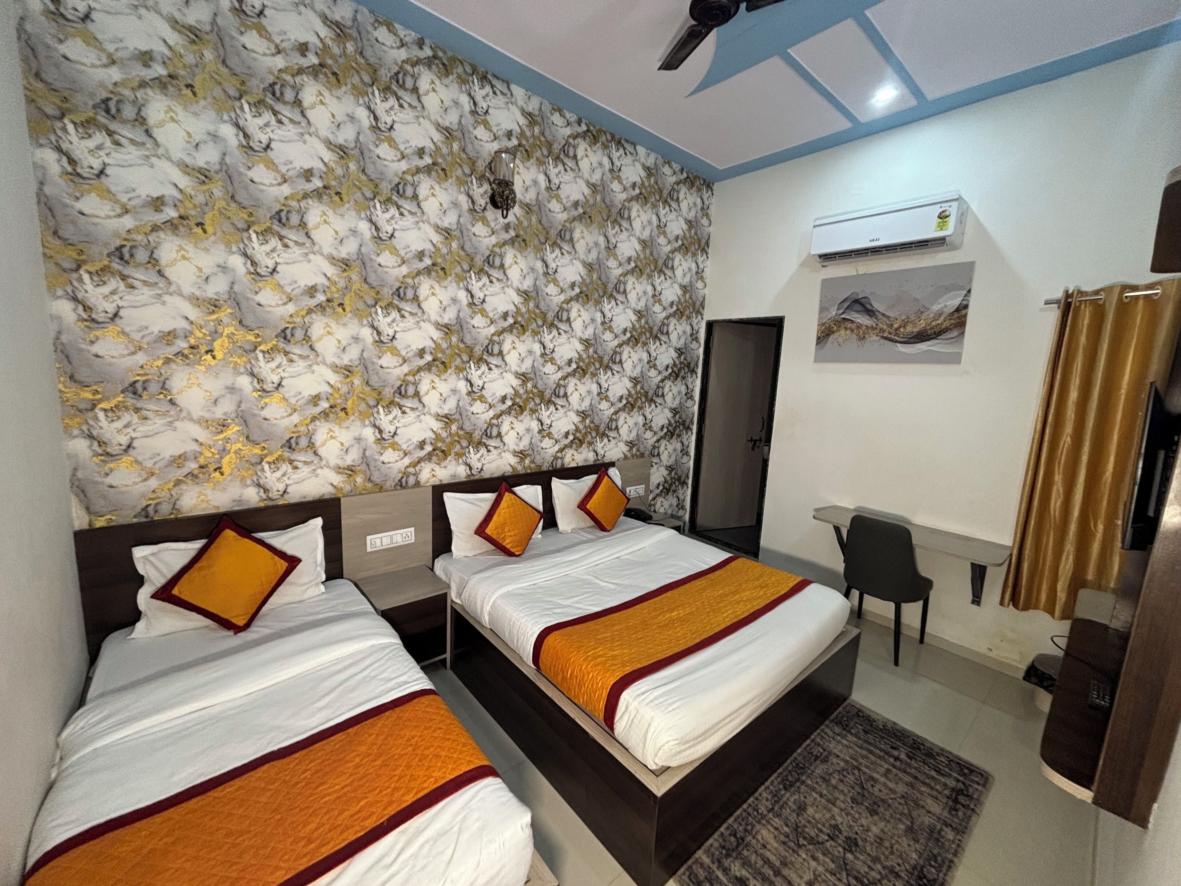 Une chambre d’hôtel avec deux lits, un bureau, une chaise, un appareil de climatisation et une porte.
