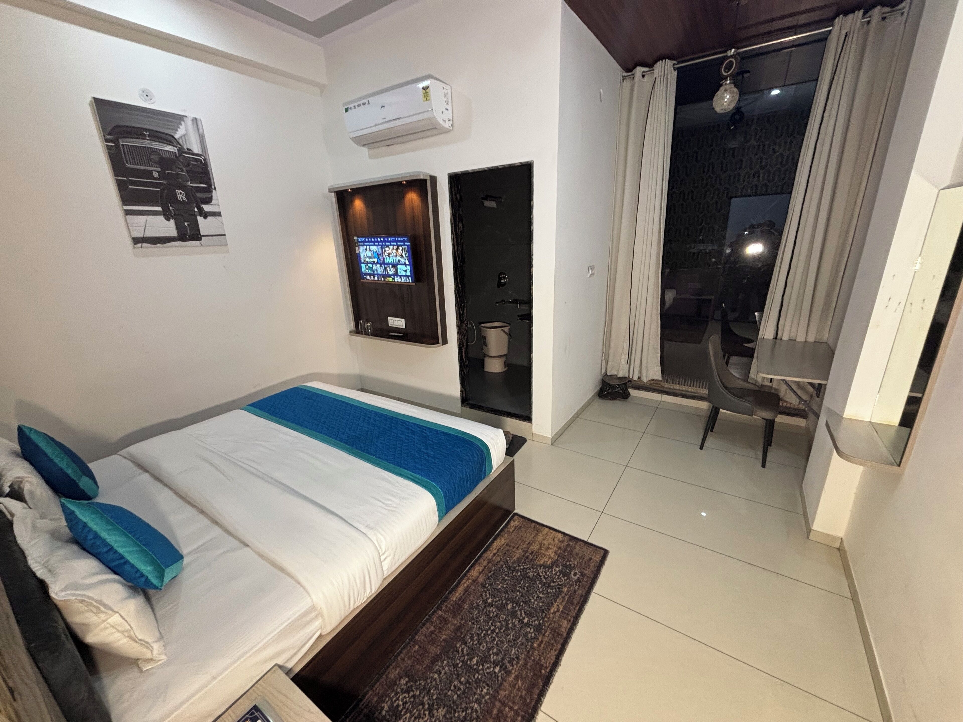 A hotel room with a bed, a TV, a small table, and a chair.