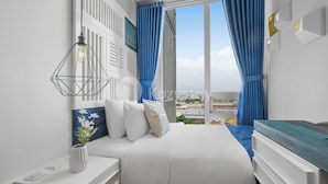 Ein modernes Schlafzimmer mit einem großen Bett, weißer Bettwäsche, einem Nachttisch mit einer Vase und Blick auf die Stadt durch große Fenster.