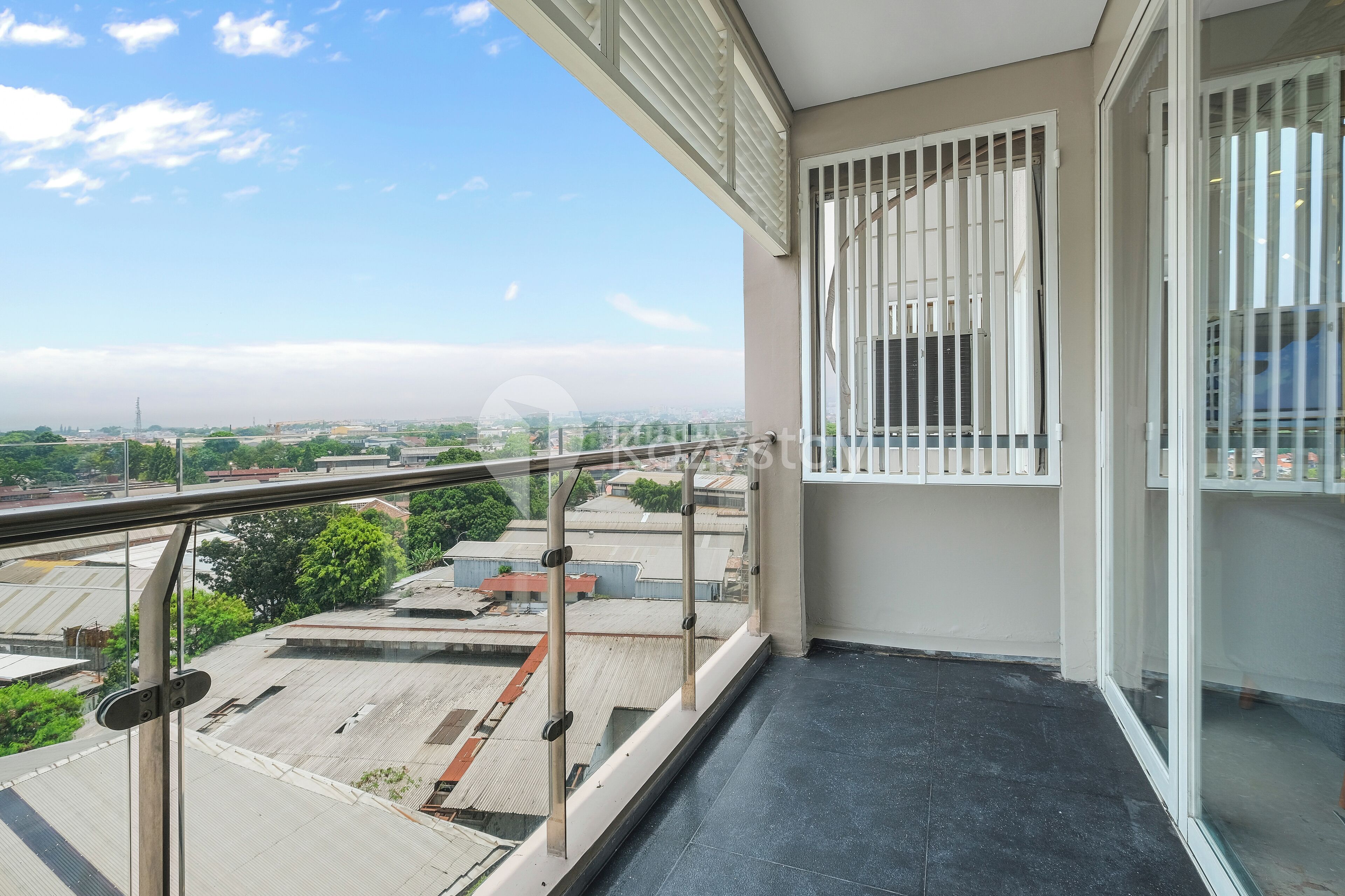 A balcony with a glass railing overlooking a cityscape.