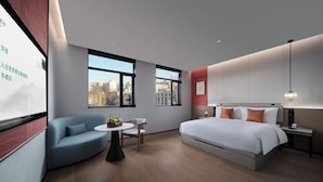 A modern hotel room with a large bed, a seating area with a table, and two large windows offering city views. - SSAW Garden Hotel Beijing (Beijing)