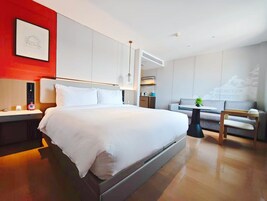 Habitación de hotel moderna con una cama grande, un escritorio, un sofá y una zona de comedor.