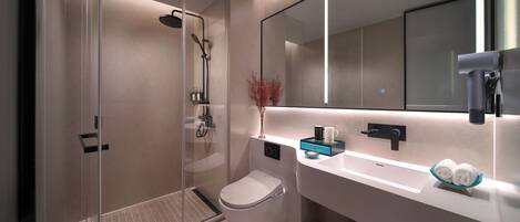 A modern bathroom with a glass-enclosed shower, a toilet, a sink with a mirror, and neatly rolled towels.