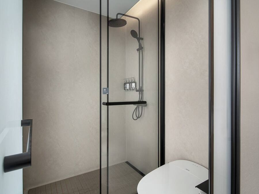 Un baño moderno con ducha acristalada, inodoro y lavabo.