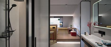 A modern bathroom with a shower, toilet, and sink. There is a mirror above the sink and a plant on the counter.