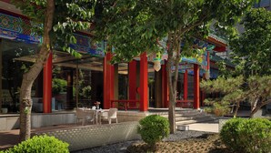 A traditional building with red columns and ornate decorations, surrounded by trees and a gravel garden. - SSAW Garden Hotel Beijing (Beijing)