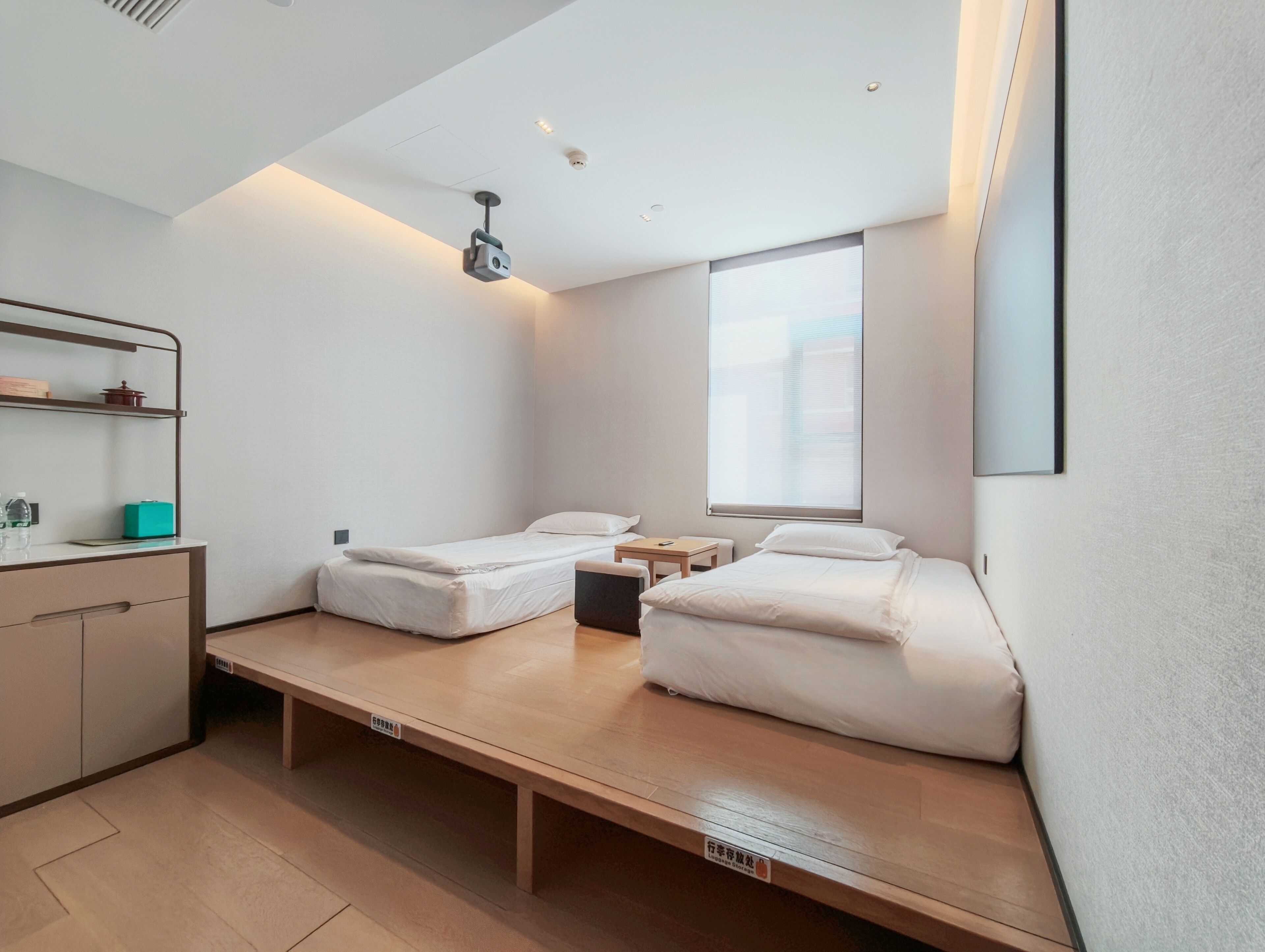Habitación de hotel pequeña con cama, mesita de noche y un escritorio.