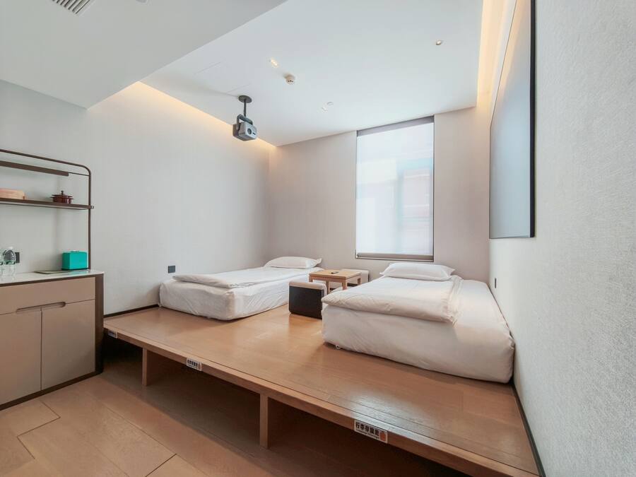 Habitación de hotel pequeña con cama, mesita de noche y un escritorio.