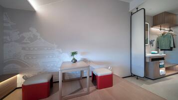 A modern room with a minimalist design, featuring a wooden table, two red ottomans, a potted plant, and a wall mural.