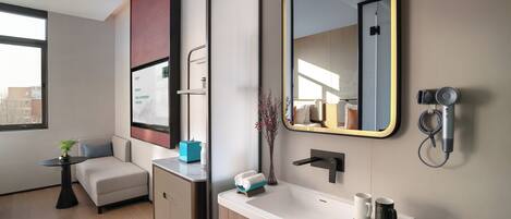 A modern bathroom with a large mirror, a sink with a towel holder, and a hairdryer mounted on the wall.