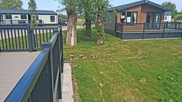 A mobile home with a fenced yard, a small tree, and a grassy area.