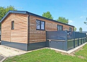 A wooden mobile home with a fenced yard, a window, and a door.
