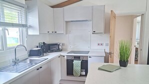 A compact kitchen with white cabinets, a built-in microwave, a dishwasher, and a sink.