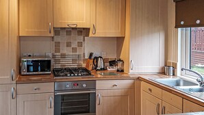 Una cocina con armarios de madera, microondas, estufa, horno y ventana con vistas.