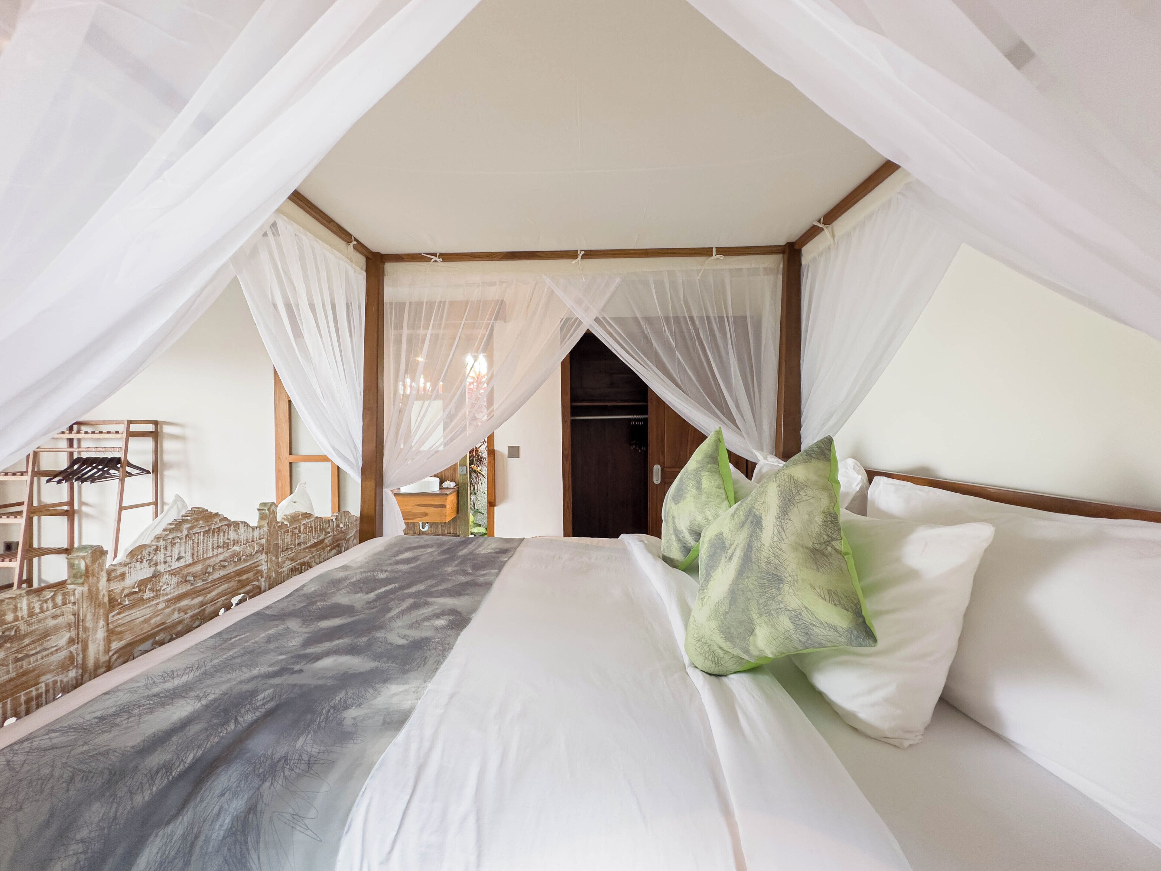 Een slaapkamer met een hemelbed, een houten hoofdbord en een nachtkastje met een lamp.