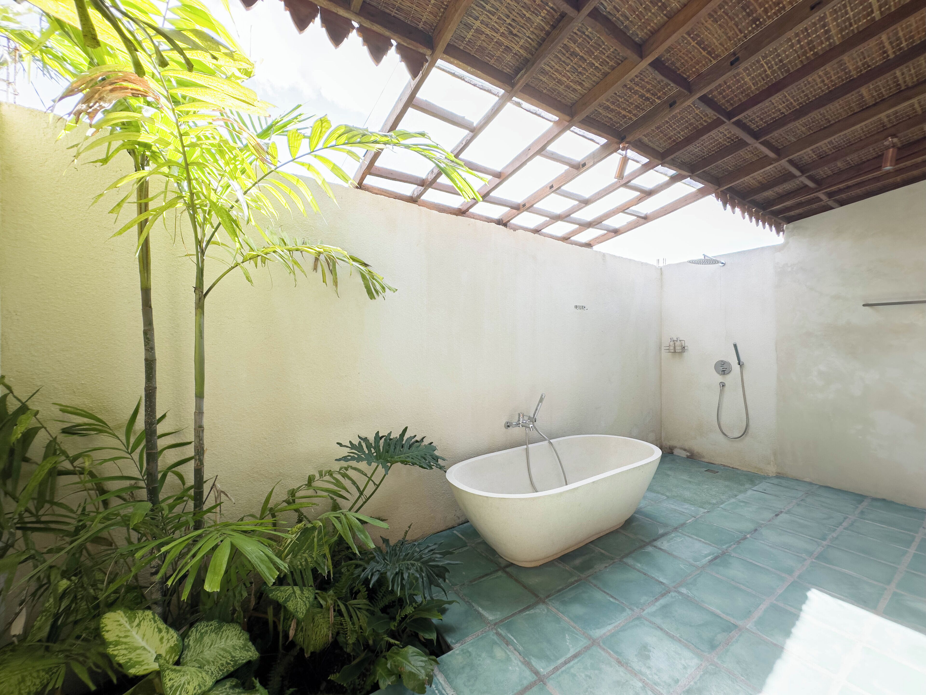 Un baño con una bañera independiente, piso de baldosas y diversas plantas.