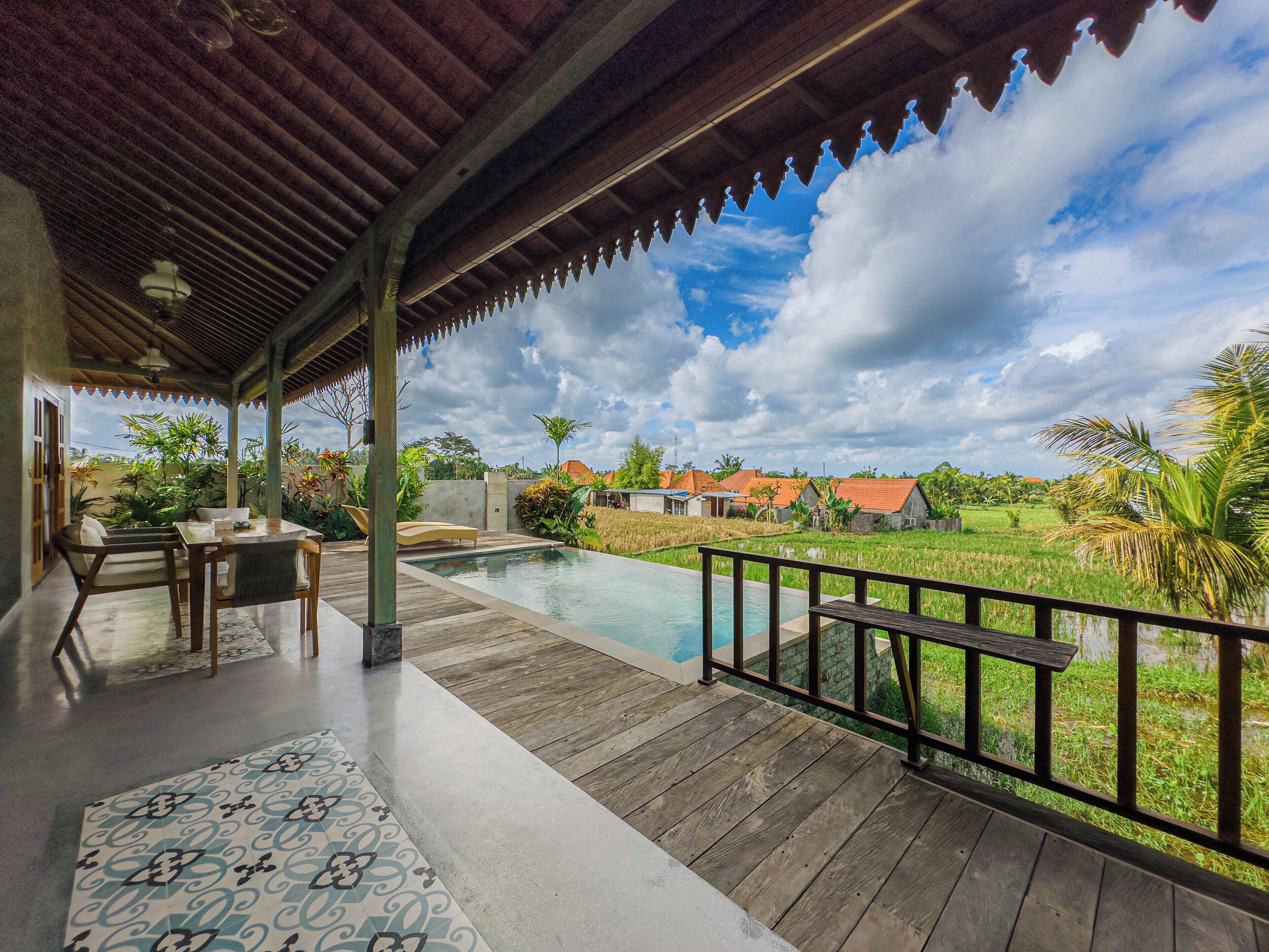 Un espace extérieur abrité comprenant une piscine, une terrasse en bois et une vue sur un paysage rural.