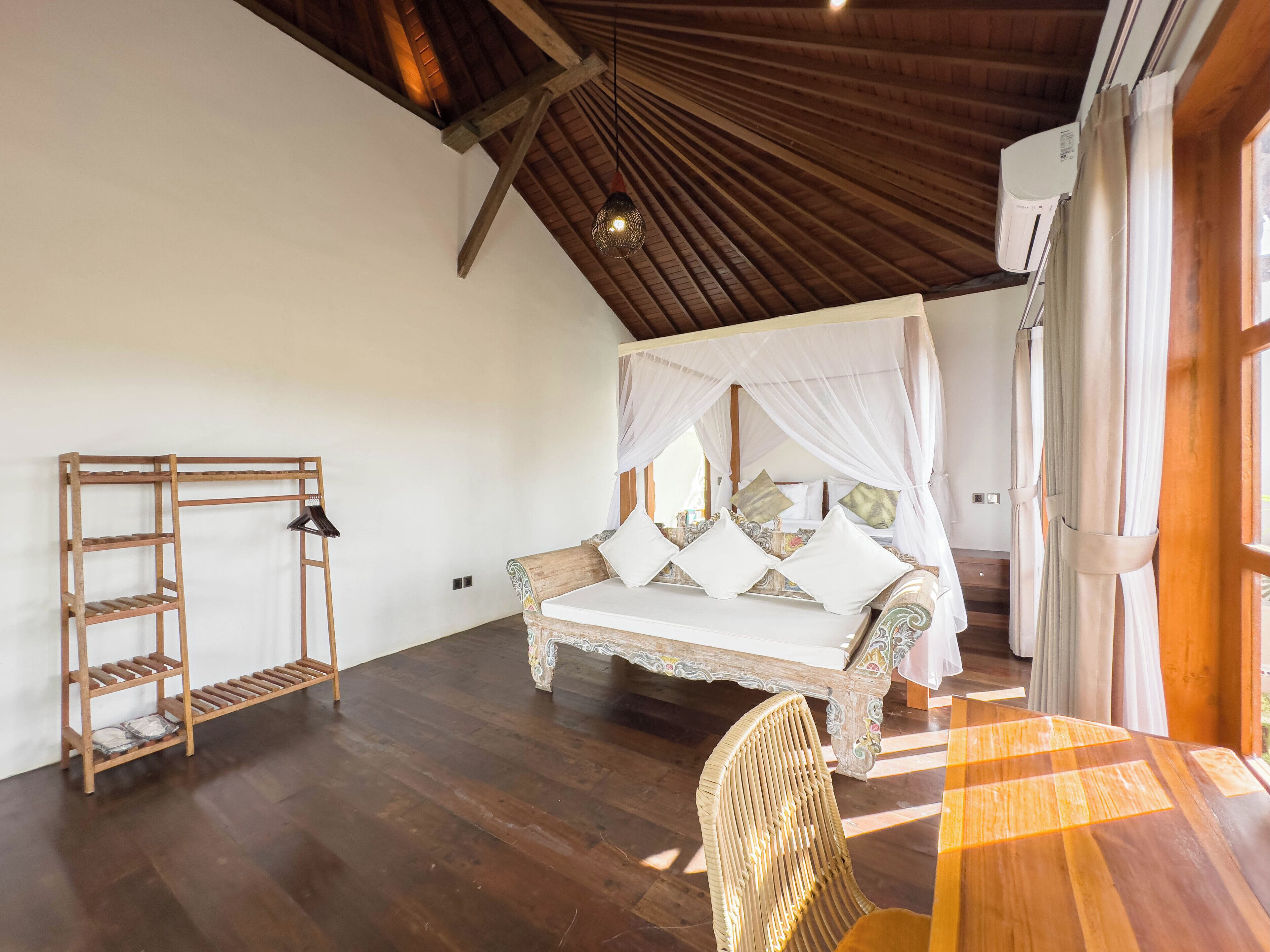Une chambre spacieuse avec un plafond en bois, un lit à baldaquin, une échelle en bois et une chaise en osier.