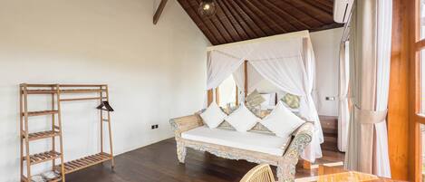 A spacious bedroom with a wooden ceiling, a four-poster bed, a wooden ladder, and a wicker chair.