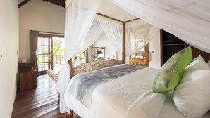 A spacious bedroom with a large bed, a wooden headboard, a bedside table, and a window with curtains. - Uma Nawasena Ubud (Ubud)
