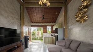 A spacious living area with a flat-screen TV, a sofa, a coffee table, and a kitchen in the background. - Uma Nawasena Ubud (Ubud)