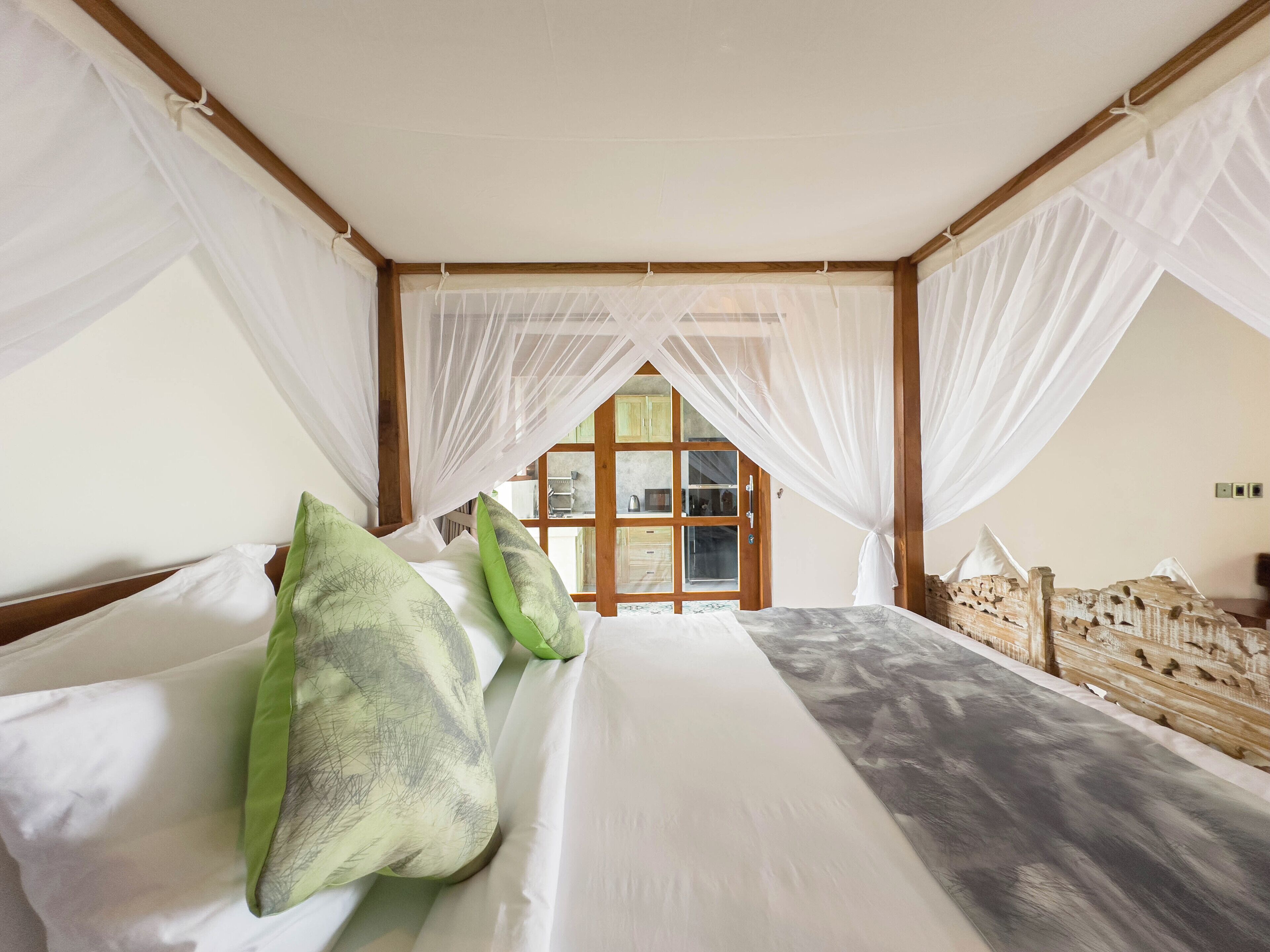 A bedroom with a large bed, white bedding, green pillows, and a wooden headboard.