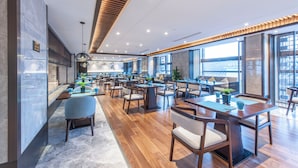 En rymlig restaurang med flera matplatser, trägolv och stora fönster som släpper in naturligt ljus.