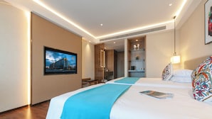 Ett hotellrum med två sängar, en TV, en bokhylla och ett skrivbord.