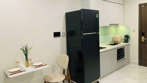 A modern kitchen with a black refrigerator, a dining table with chairs, and a small side table with a vase.