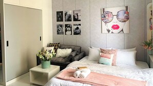 A modern bedroom with a bed, a sofa, a nightstand, and a wardrobe.