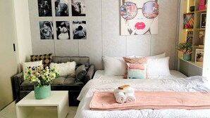A modern bedroom with a bed, a sofa, a coffee table, and a wall with framed photos.