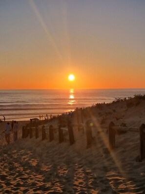 A beach at sunset with people walking along the shore.