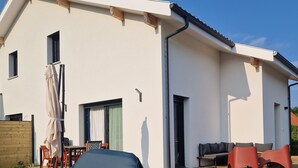 Una casa moderna con techo plano, un patio cubierto con mobiliario exterior y una piscina inflable grande.