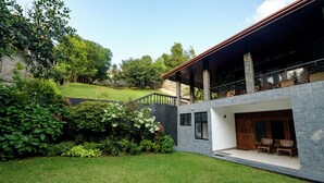 Une maison moderne dotée d’un patio couvert, d’un garage et d’une pelouse bien entretenue.
