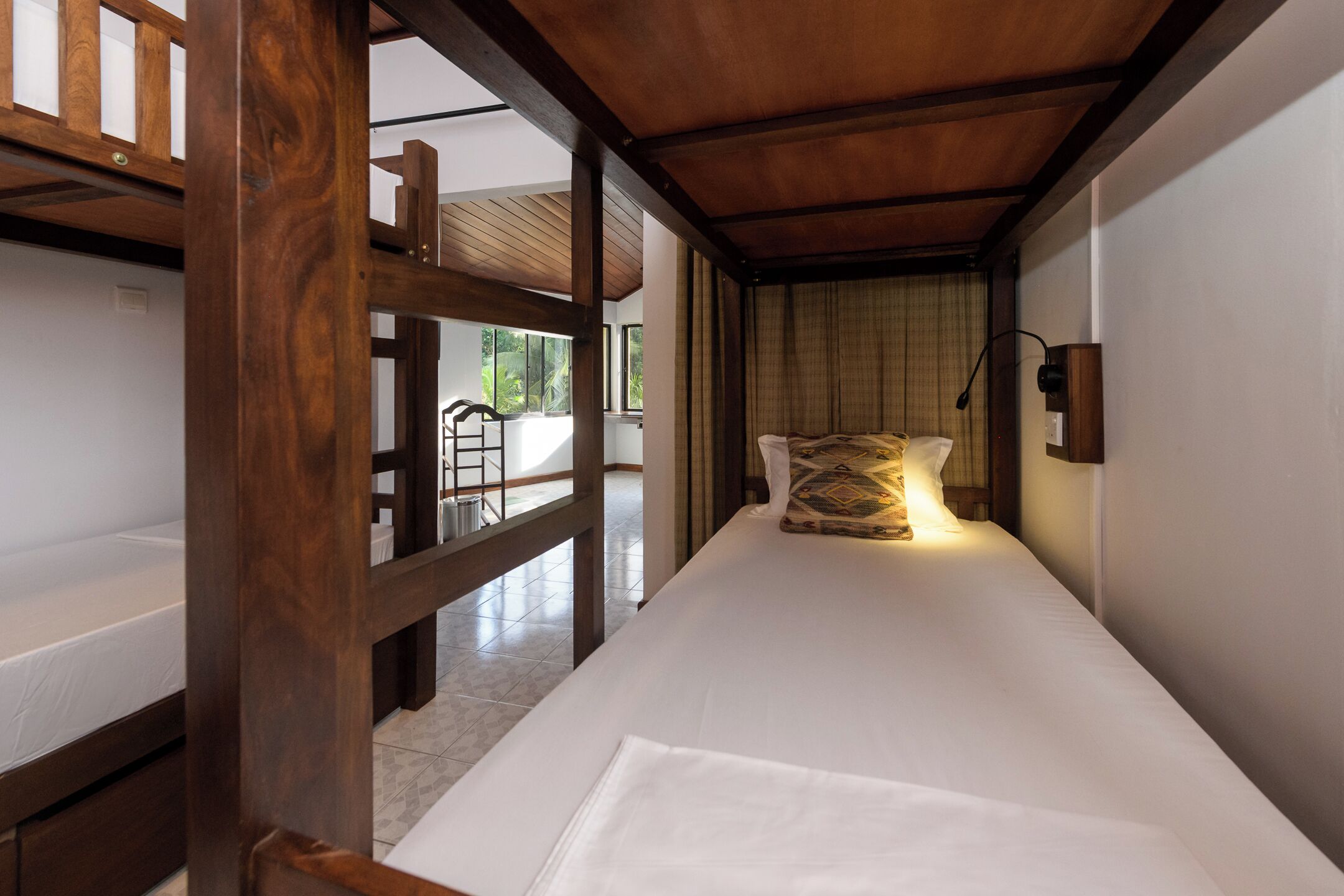 A single bed with a wooden headboard, a bedside table, and a wall-mounted lamp.