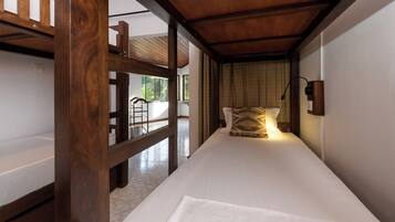 A single bed with a wooden headboard, a bedside table, and a wall-mounted lamp.