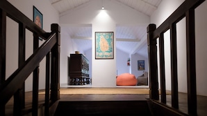 Un escalier menant à une pièce dotée d’un plancher en bois, d’une œuvre d’art encadrée au mur et d’un fauteuil en forme de sac de haricots.