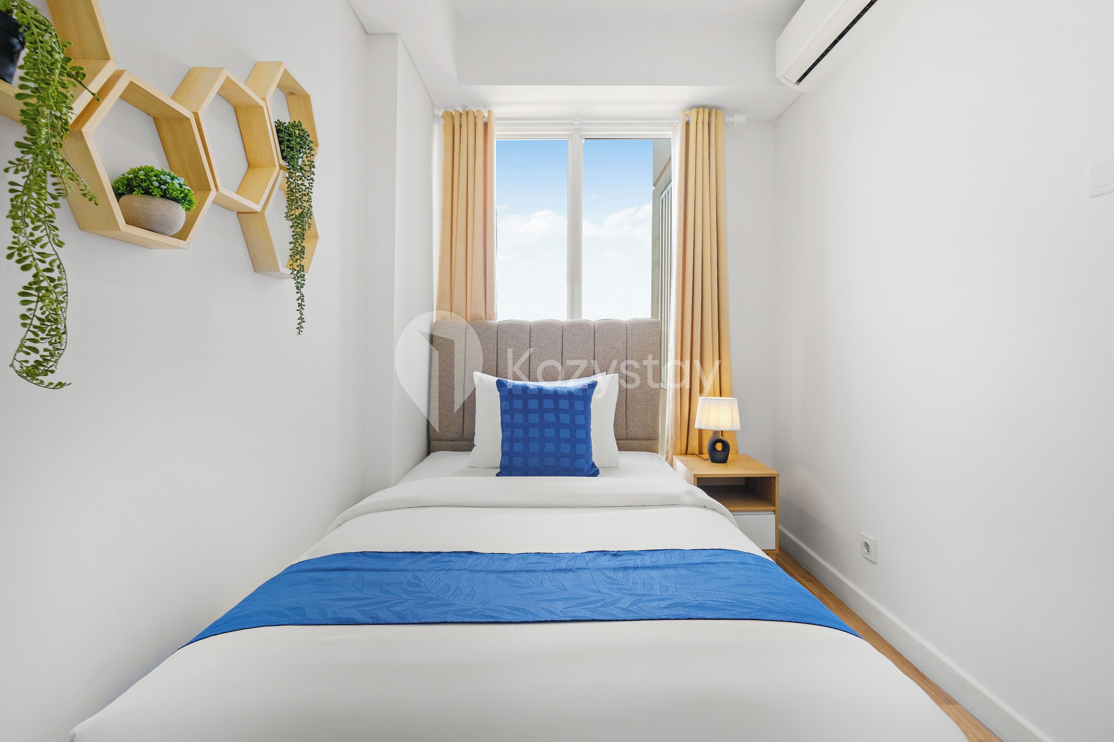 A modern hotel room with a large bed, a bedside table with a lamp, and a window with curtains.