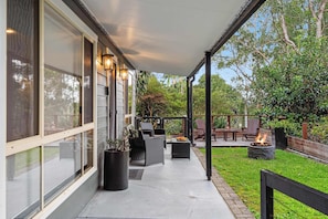 Eine überdachte Terrasse mit Gartenmöbeln, einer Feuerstelle und Blick auf die umliegende Natur.