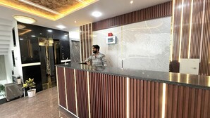 A reception desk with a modern design, a digital screen, and a potted plant. - THE GRAND LUXURY STAY HOTEL (Agra)