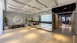A modern reception area with a wooden bench, potted plants, and a large mirror reflecting the interior.