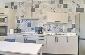 Una cocina moderna con armarios blancos, horno empotrado, cafetera y tostadora.