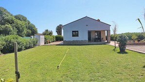 A single-story house with a white exterior, a stone base, and a small porch with a table and chairs. - Casa Marcucaña el Palmar (El Palmar)