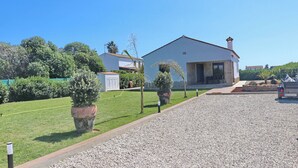 A residential property with a gravel driveway, a well-maintained lawn, and a house with a chimney. - Casa Marcucaña el Palmar (El Palmar)